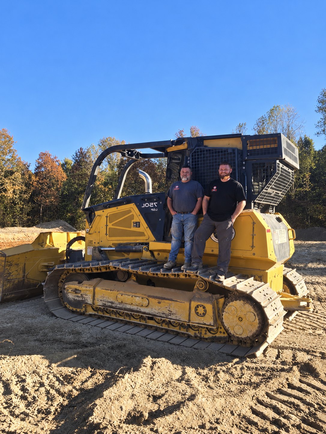 Snead's Outdoor Services crew standing on a dozer at a job site