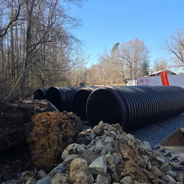 Corrugated drainage culverts stockpiled beside stone on a job site