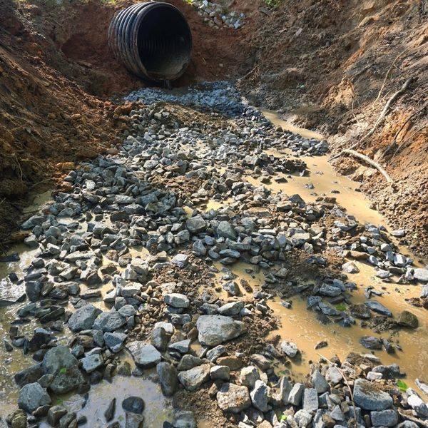 Riprap stone set into a drainage channel below a culvert outlet