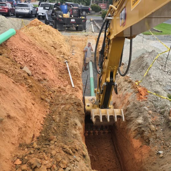 Excavator digging a utility trench beside a residential street