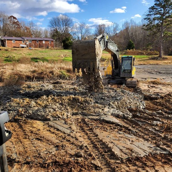 Excavator clearing burnt debris from a cleared lot