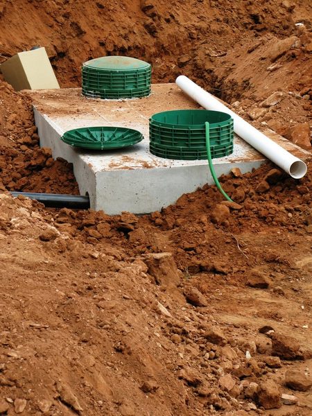 Concrete septic tank lid with green riser caps and PVC inlet