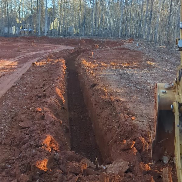 Deep trench cut through red clay for a utility run