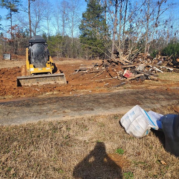 Skid steer stacking cleared brush and timber into a pile