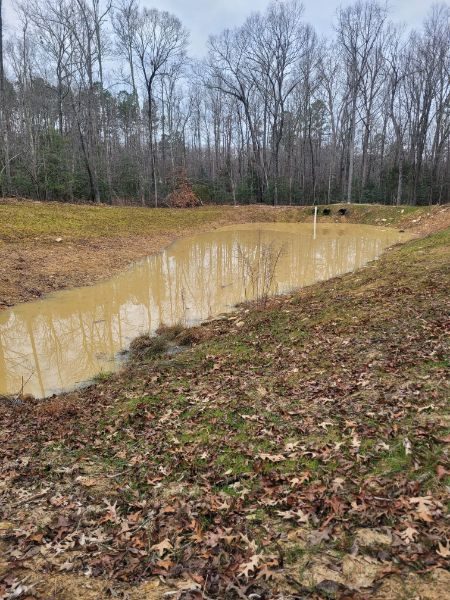 New pond filling with water against its finished banks