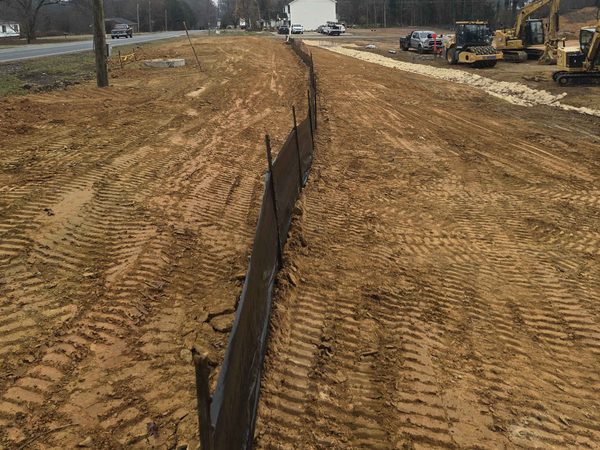 Silt fence trenched in along the edge of a graded site