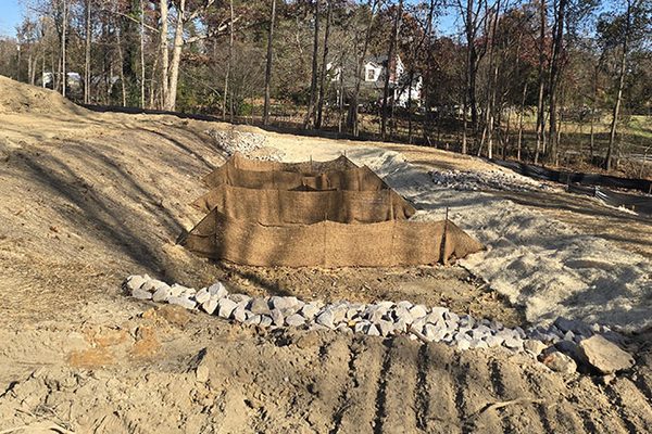 Sediment barrier and riprap check dam holding a graded slope